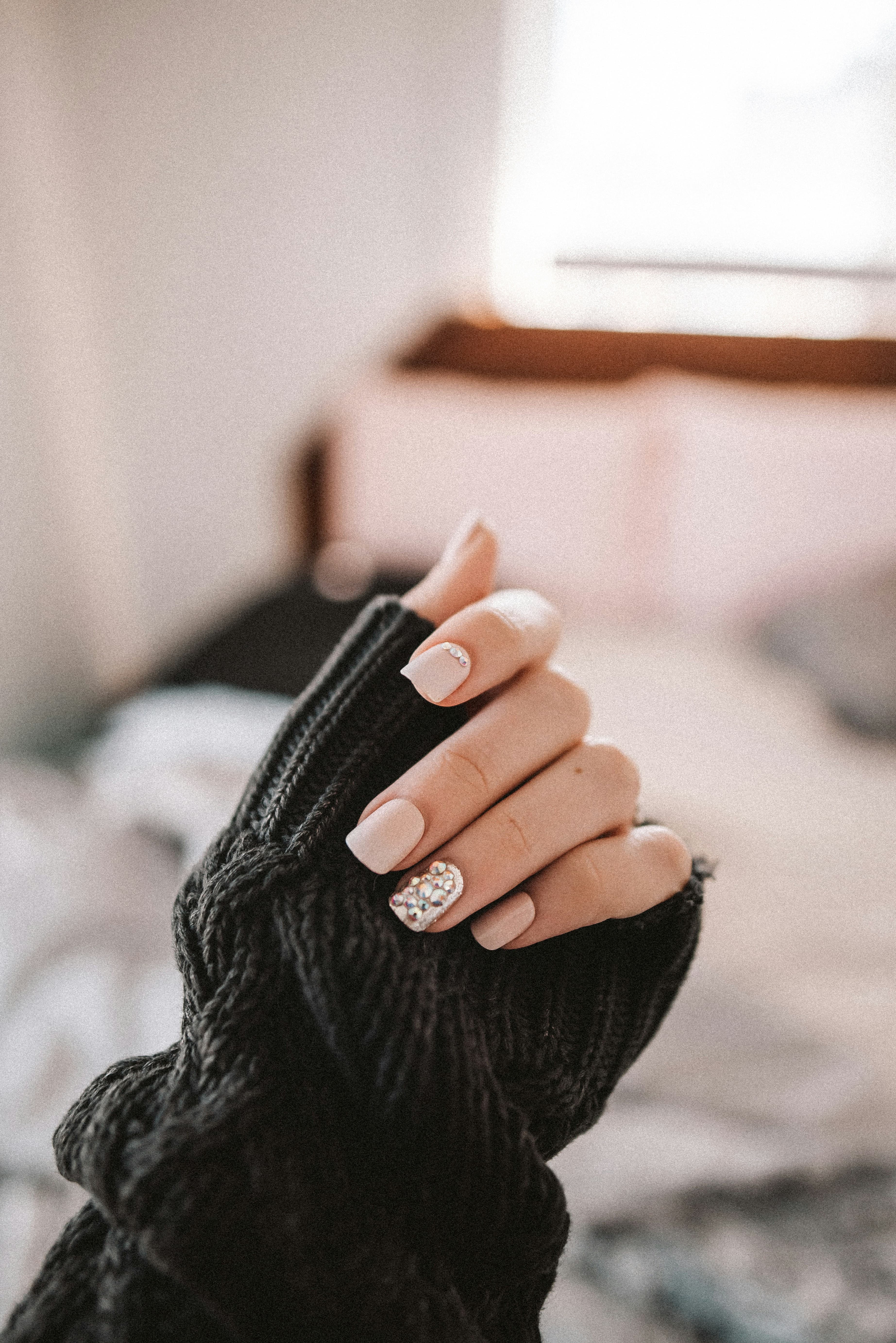 Short white and glitter polish against a dark sweater