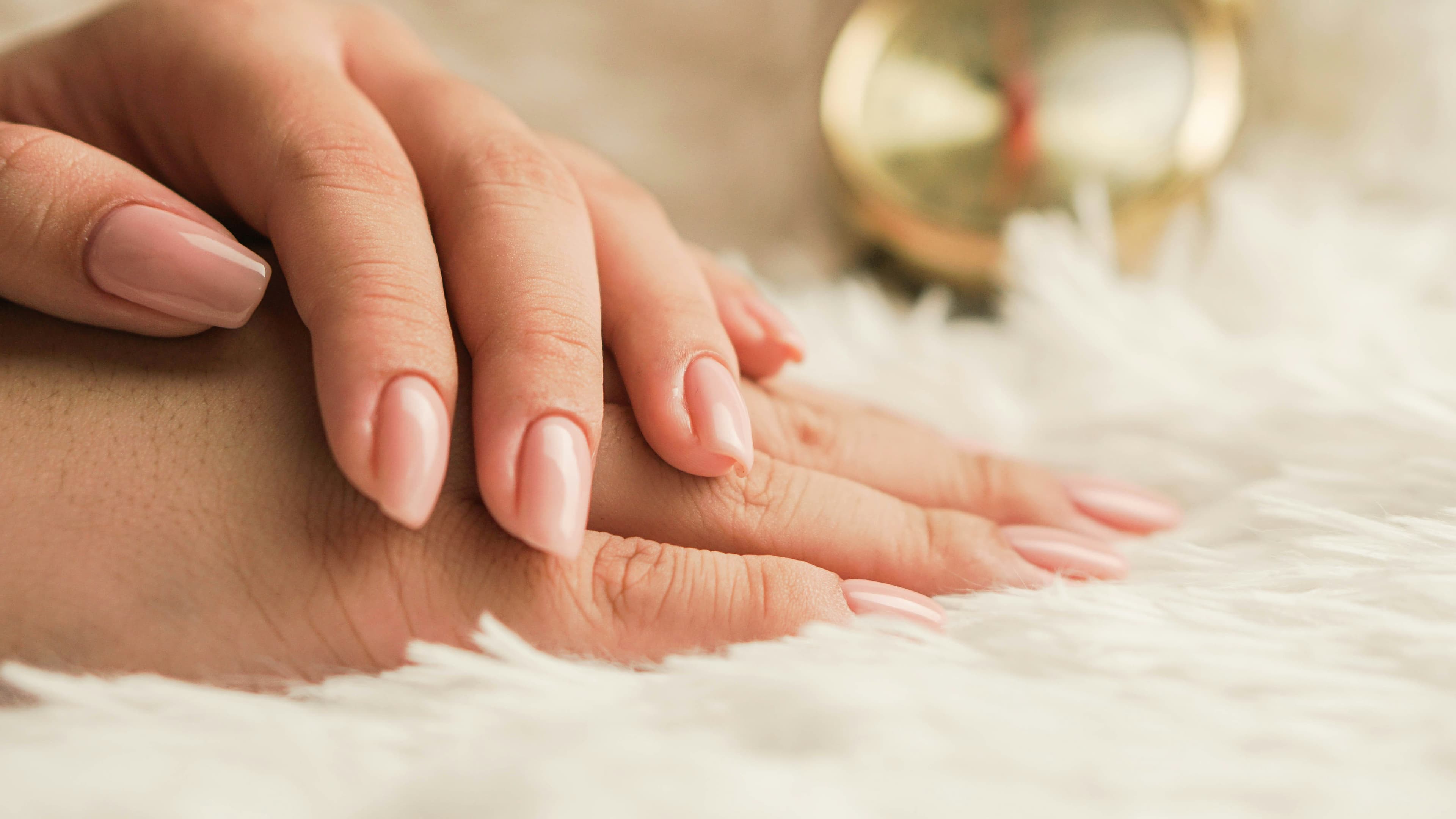 Short gel manicure on a hand resting on white fabric